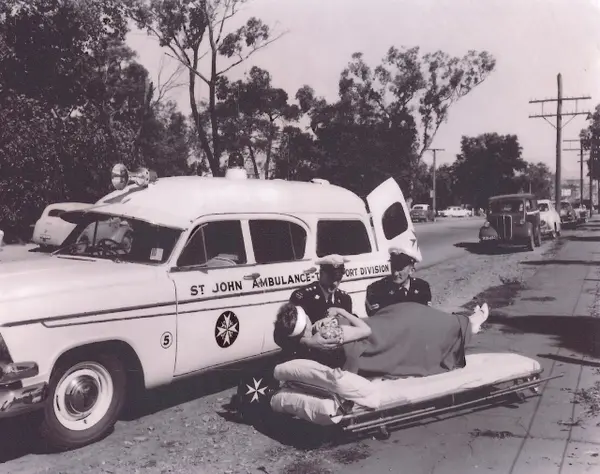 Vintage St John ambulance crew attending to a patient on a stretcher